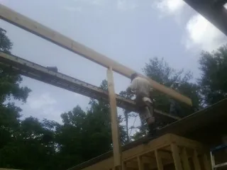 Carpenter setting a ridge beam over a new addition frame — Ice Dam Removal by Roofing Brothers in Pierson