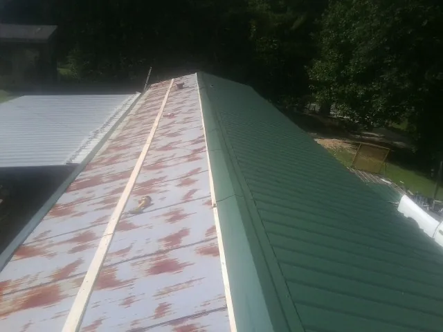 Old rusted panels beside newly installed green metal roofing — Wind Damage Roof Repair by Roofing Brothers in Pierson