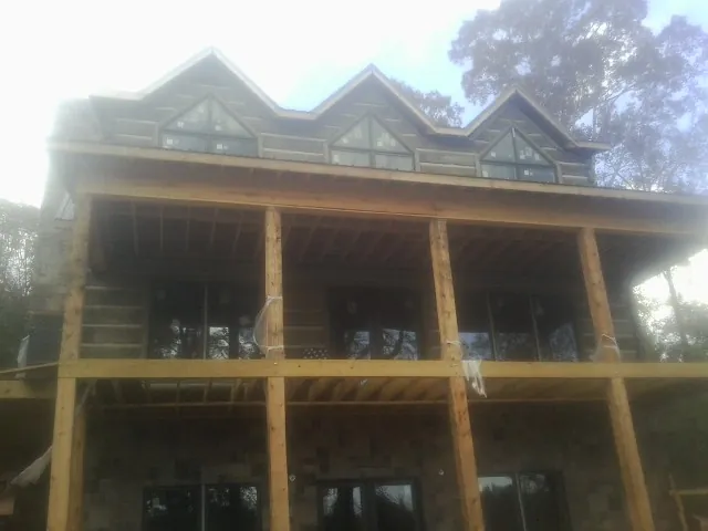 Dormers and porch framing on a large log home under construction — Roof Coating work by our crew in Pierson