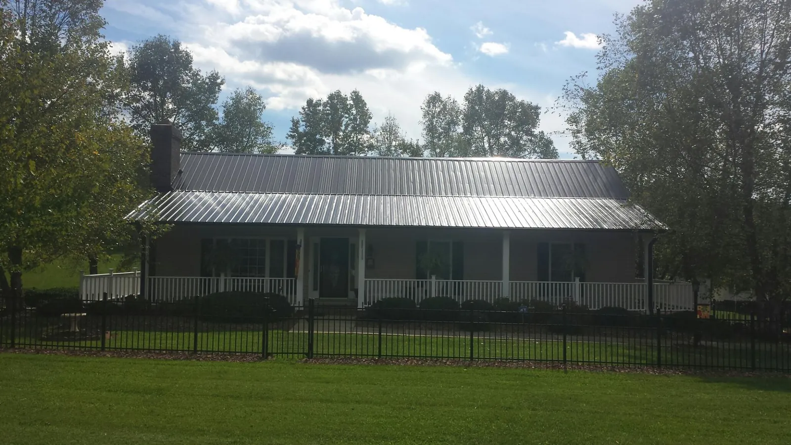 Gray metal roof on a brick ranch with a full width front porch — Gutter Guard Installation work by our crew in Pierson